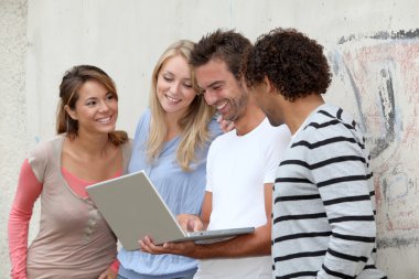 Group of friends standing with laptop computer clipart