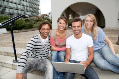 Friends sitting in college campus with laptop computer clipart