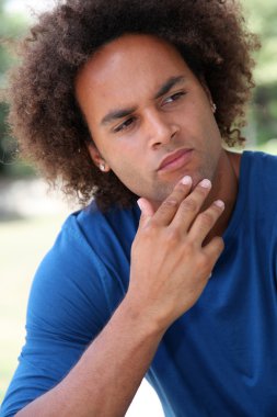 Young man thinking in a park clipart