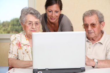 Couple of elderly persons and young woman with laptop computer