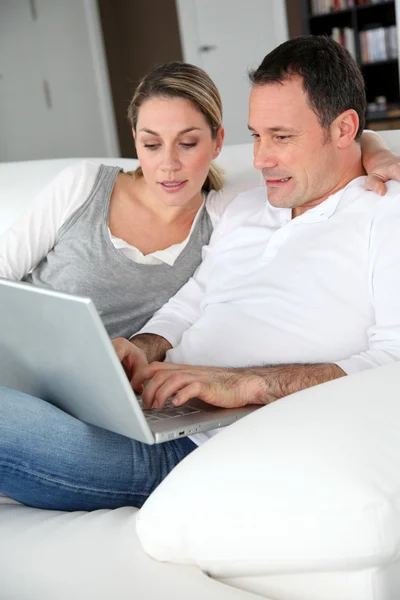 Couple relaxing in sofa with laptop computer — Stock Photo, Image