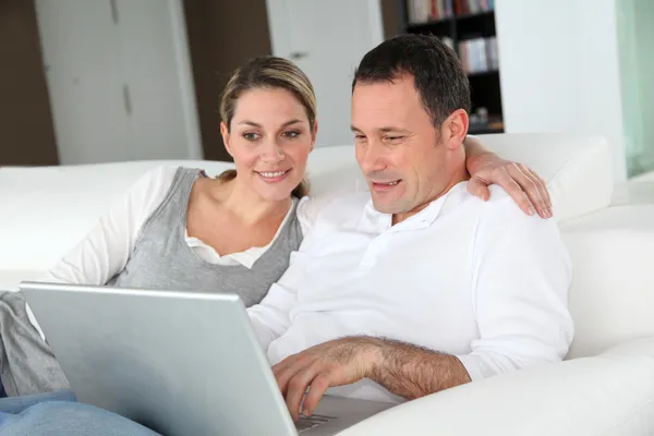 Couple relaxing in sofa with laptop computer — Stock Photo, Image