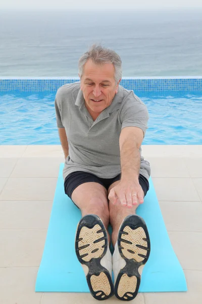 Старший делает упражнения у бассейна — стоковое фото