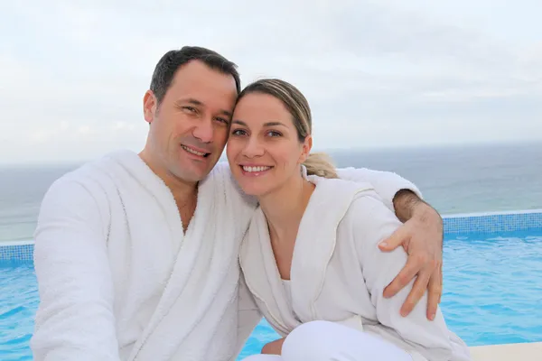 Paar in badjas zitten bij het zwembad — Stockfoto