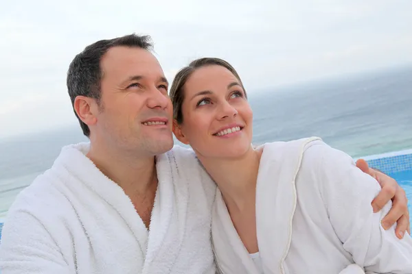 Par i morgonrock sitter vid poolen — Stockfoto
