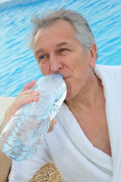 Старший мужчина черпает воду из бутылки — стоковое фото