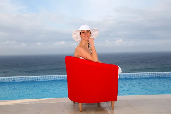 Hermosa mujer relajándose en silla roja — Foto de Stock