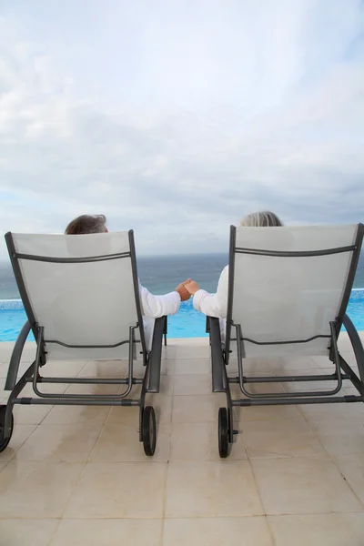 Senior couple relaxing in long chairs — Stock Photo, Image