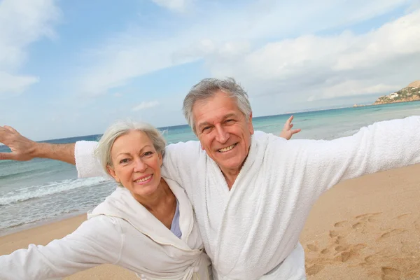 Starší pár v županu na pláži — Stock fotografie