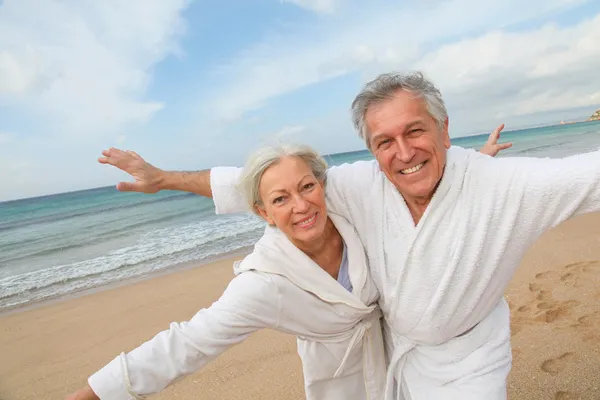 Старшая пара в халате на пляже — стоковое фото