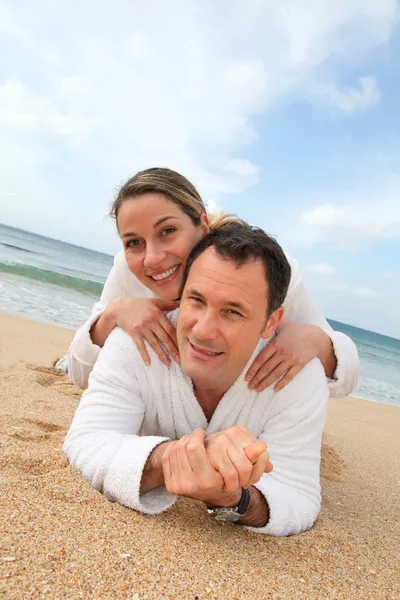 Par avkopplande i morgonrock på stranden — Stockfoto