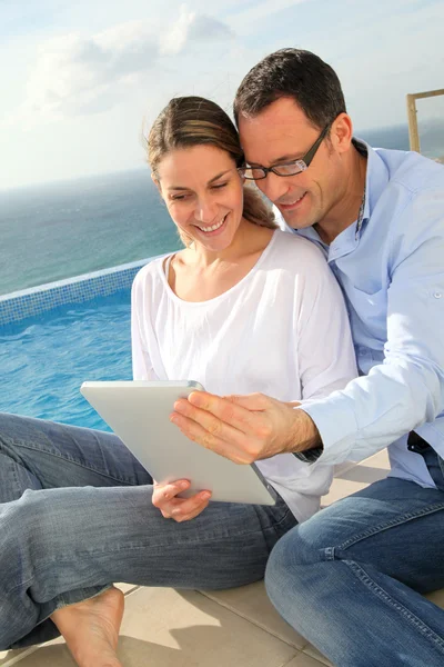 Szczęśliwa para przy użyciu elektronicznych tabletki przy basenie — Zdjęcie stockowe