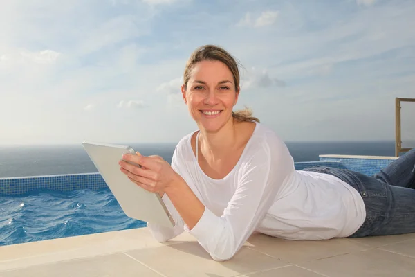 Γυναίκα με τη χρήση ηλεκτρονικών δισκίο από την πισίνα — Φωτογραφία Αρχείου