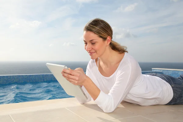 Vrouw met behulp van elektronische tablet door zwembad — Stockfoto