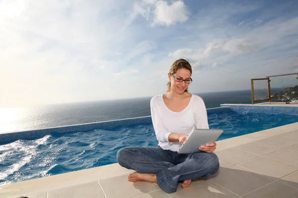 Женщина с помощью электронного планшета у бассейна — стоковое фото