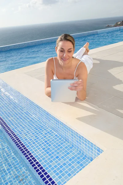 Kobieta za pomocą elektronicznego tabletki przy basenie — Zdjęcie stockowe