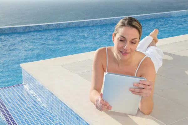 Mujer usando tableta electrónica en la piscina —  Fotos de Stock