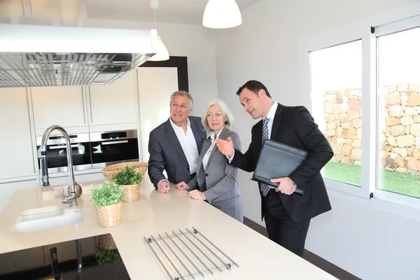 Immobilienmakler zeigt Senioren-Paar das Innere des Hauses — Stockfoto