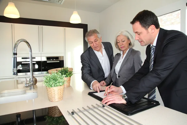 Real-estate agent showing interior of house to senior couple — Stock Photo, Image