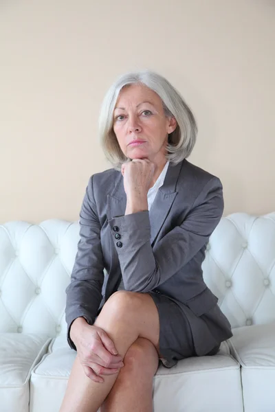 Senior woman sitting in white sofa — Stock Photo, Image