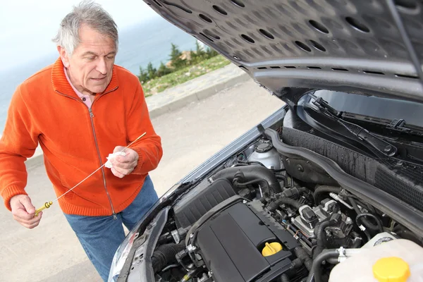 Старший чоловік перевіряє рівень двигуна автомобіля — стокове фото