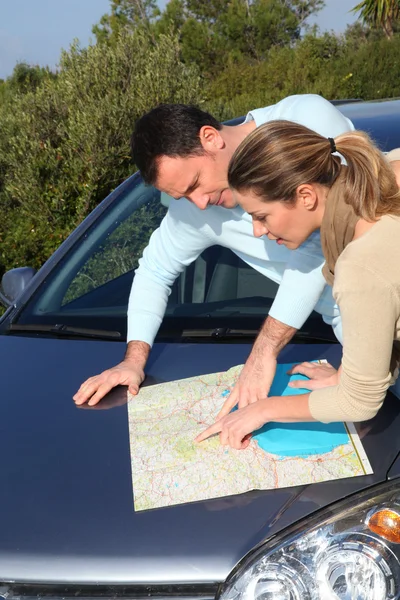 Paar kijken naar routekaart op auto kap — Stockfoto