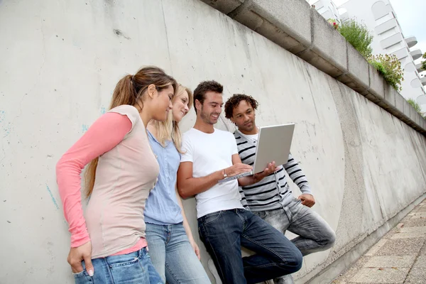 Group of friends standing with laptop computer — Stock Photo, Image