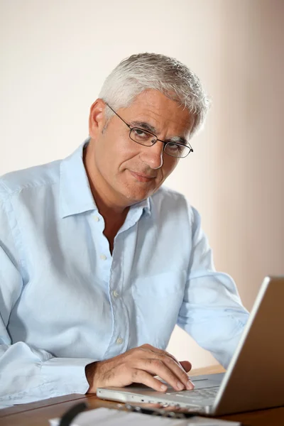 Старший чоловік перед портативним комп'ютером — стокове фото