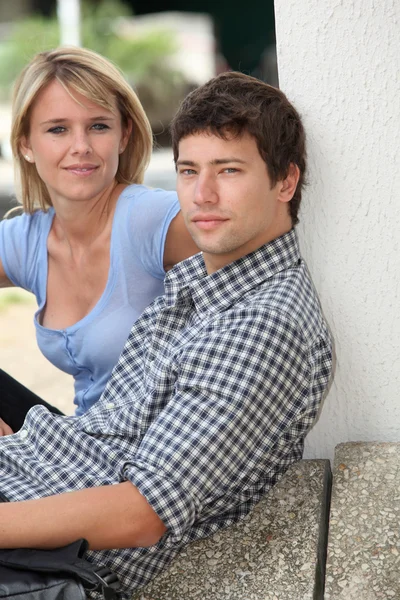 Unga paret sitter i campus gård — Stockfoto