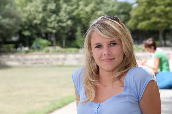 Schöne blonde Frau sitzt in einem Park — Stockfoto