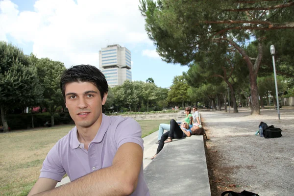 Ung man sitter i en park — Stockfoto