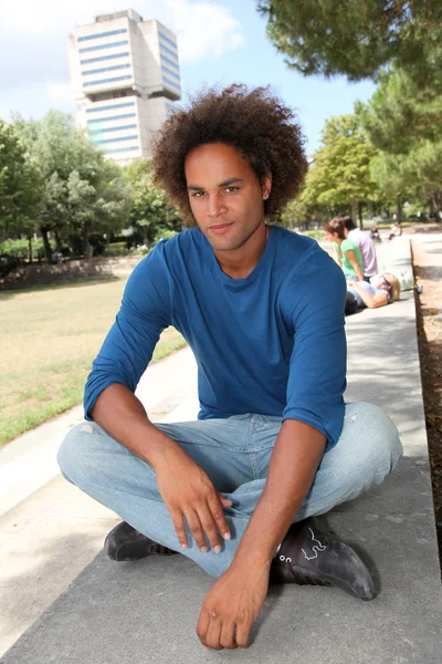 Młody człowiek siedzi w parku — Zdjęcie stockowe