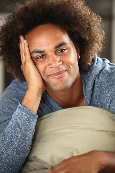 Mladý usmívající se muž v gauči — Stock fotografie
