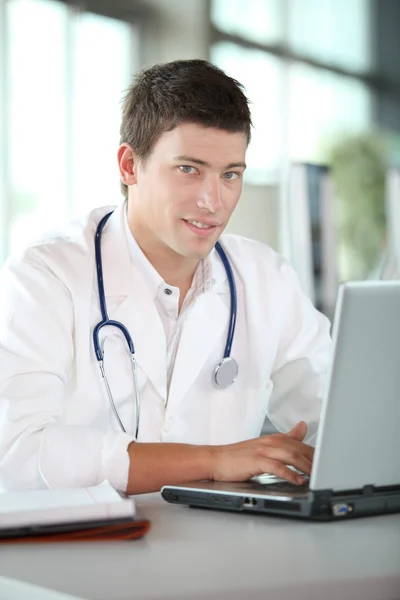 Mladý lékař před přenosný počítač — Stock fotografie