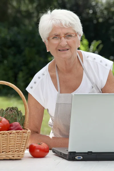 Пожилая женщина с корзиной свежих овощей — стоковое фото