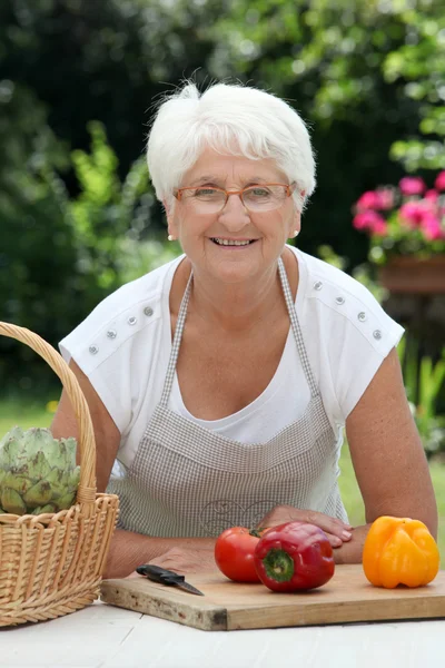 Літня жінка з кошиком зі свіжих овочів — стокове фото