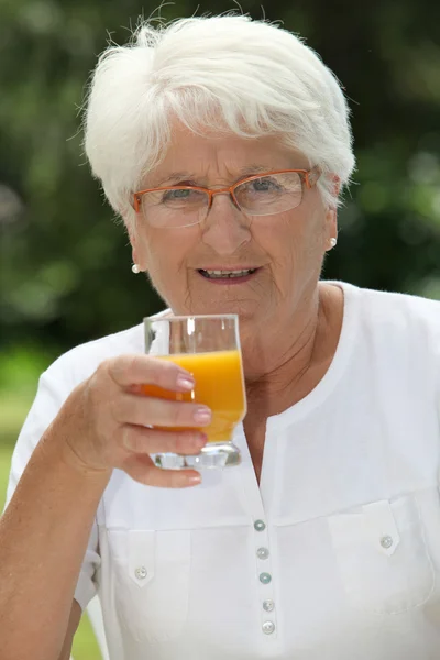 Ηλικιωμένη γυναίκα πίνοντας χυμό φρούτων — Φωτογραφία Αρχείου