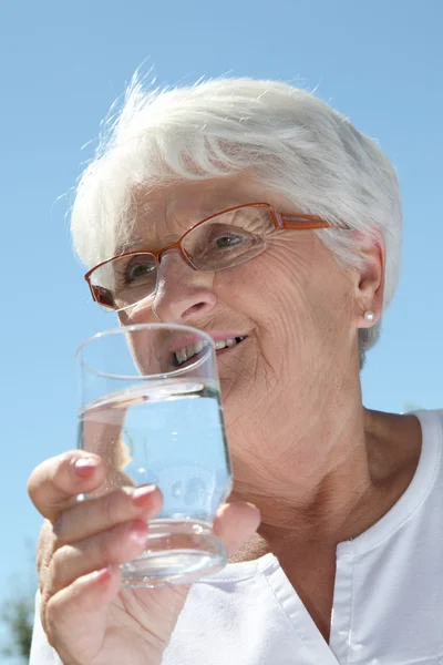 Пожилая женщина пьет wate — стоковое фото