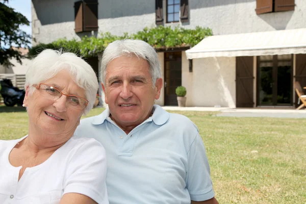 Старшая пара сидит перед домом — стоковое фото