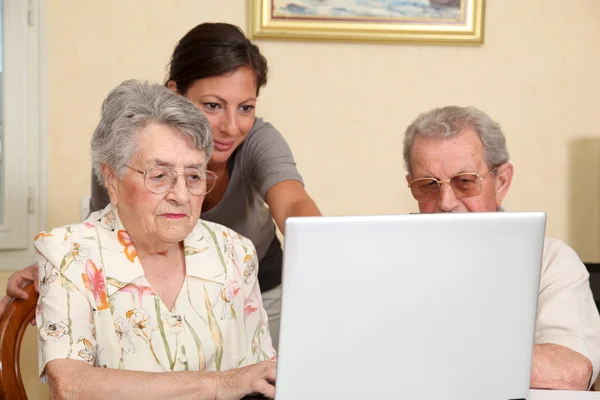 Pareja de personas mayores y mujer joven con ordenador portátil — Foto de Stock