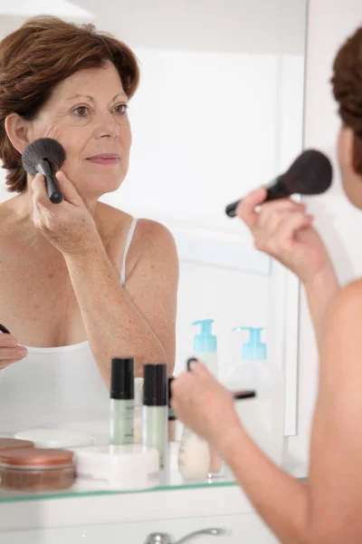 Mulher sênior colocando maquiagem — Fotografia de Stock
