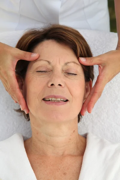 Senior vrouw met een gezicht massage — Stockfoto