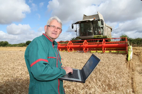 Γεωργός στέκεται στον τομέα του σίτου με υπολογιστή — Φωτογραφία Αρχείου