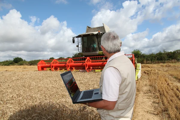 Uomo in piedi nel campo di grano con il computer — Foto Stock