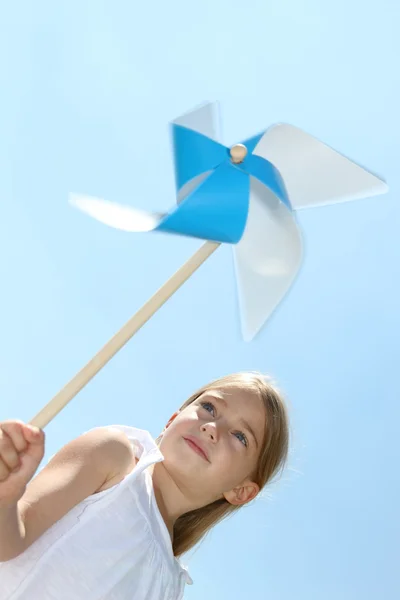 Little girl blowing blue wind wheel — Stock Photo, Image