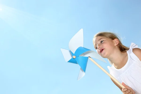 Menina soprando roda de vento azul — Fotografia de Stock