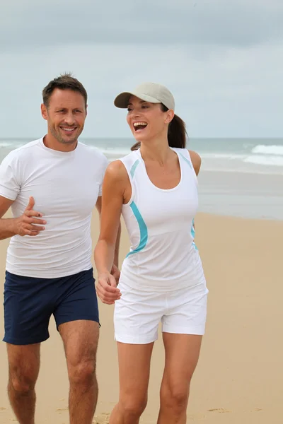 Paar joggt an einem Sandstrand — Stockfoto