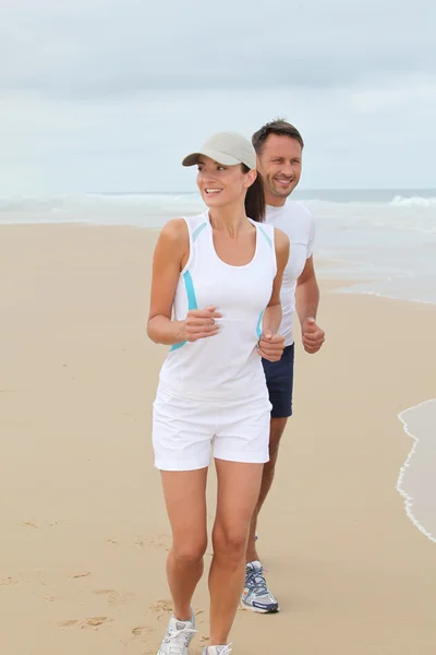 Couple jogging on a sandy beach — Stock Photo, Image