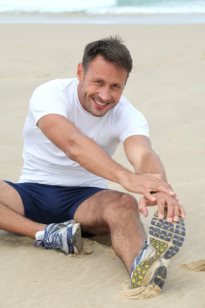 Muž táhnoucí se na pláži — Stock fotografie