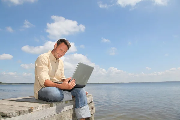 Man with laptop on a pontoon — Stock Photo, Image